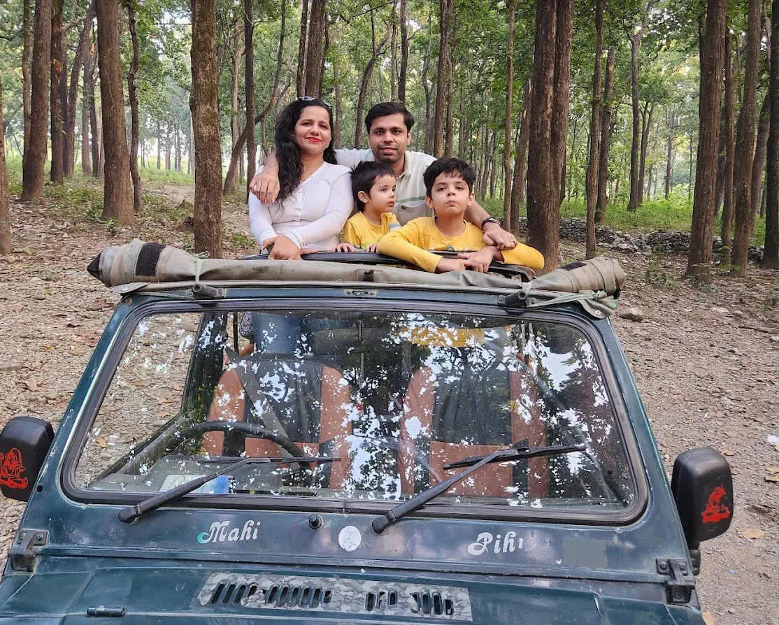 A family standing up through the roof of an open jeep on a safari through a sal forest