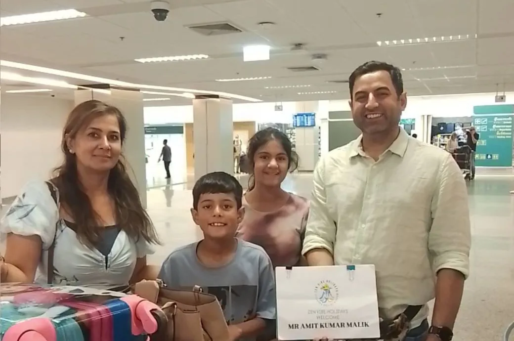 A family of four holding a Zen Vibe Holidays welcome sign at Krabi International Airport