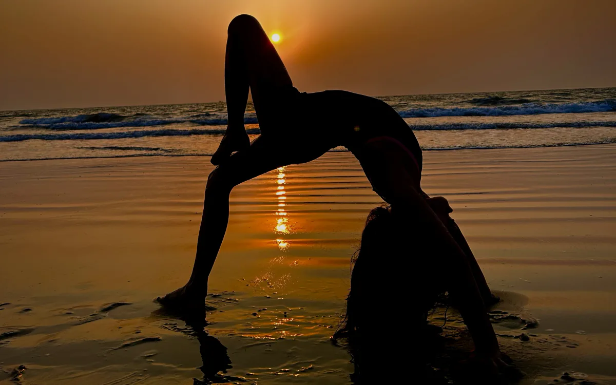 A yoga pose silhouetted on the beach at sunset